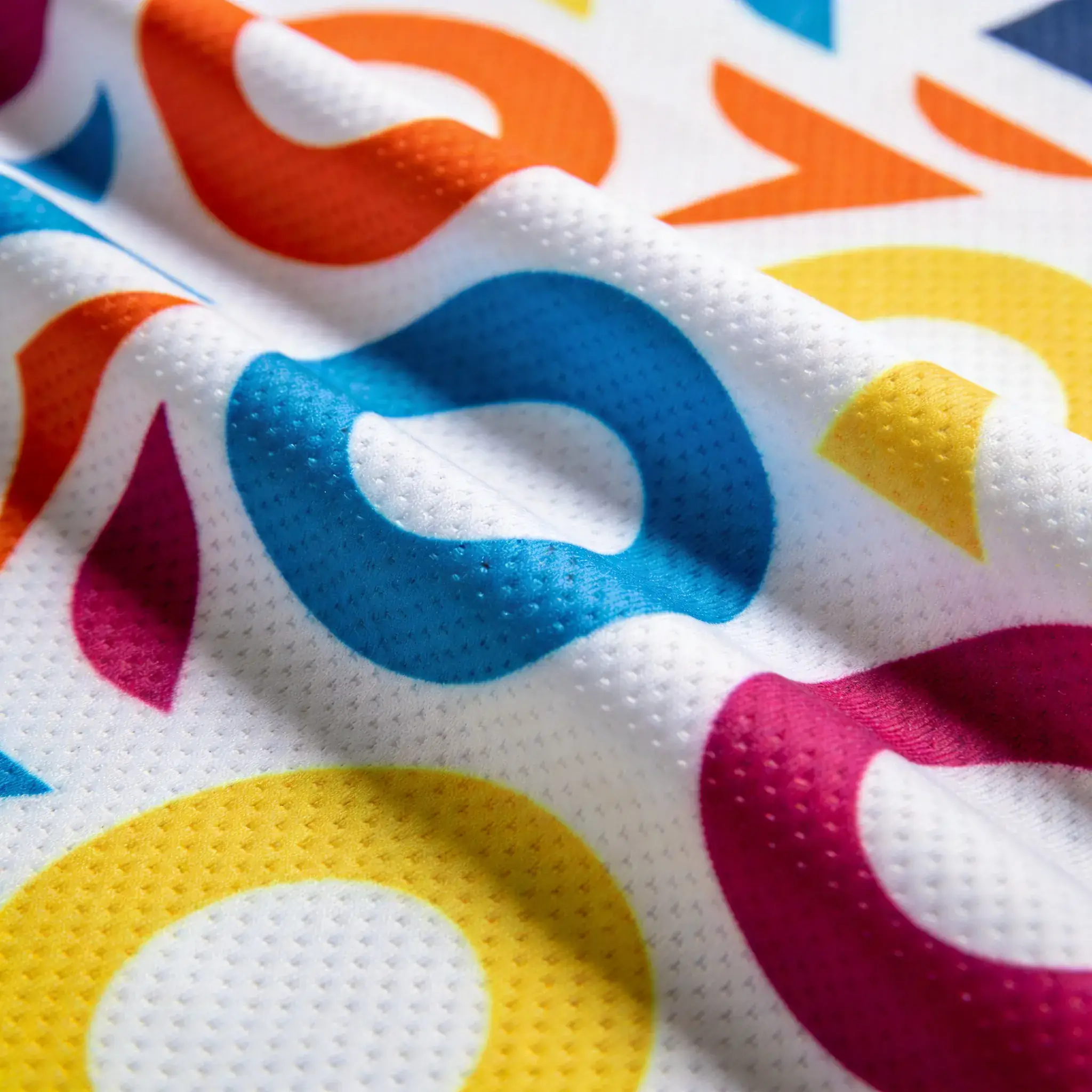 Close-up of full-sublimation polyester fabric — vivid print on white, knit texture visible
